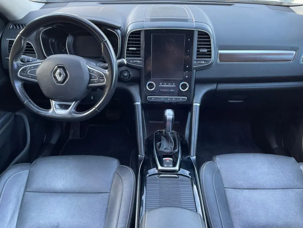 Vue intérieure avant du Renault Koleos 2019, tableau de bord noir avec écran tactile vertical et volant multifonction.