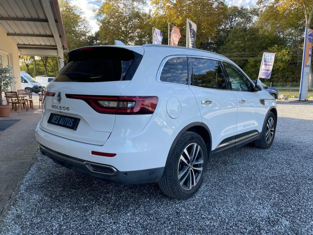 Renault Koleos blanc vu en 3/4 arrière droit, avec vitres teintées et jantes alliage distinctives.