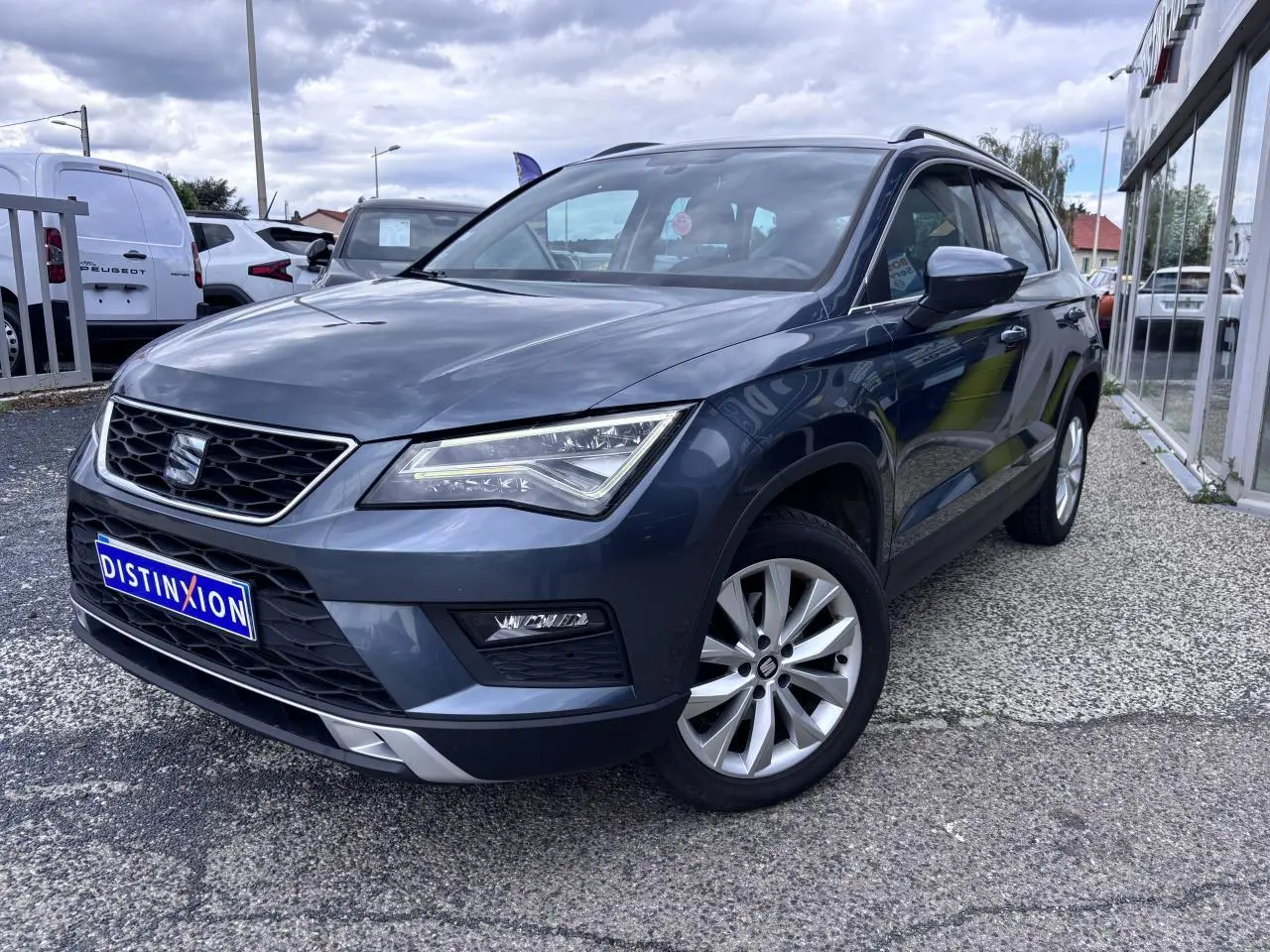 SEAT Ateca gris foncé en 3/4 avant droit, avec calandre noire et jantes alliage 17 pouces visibles.