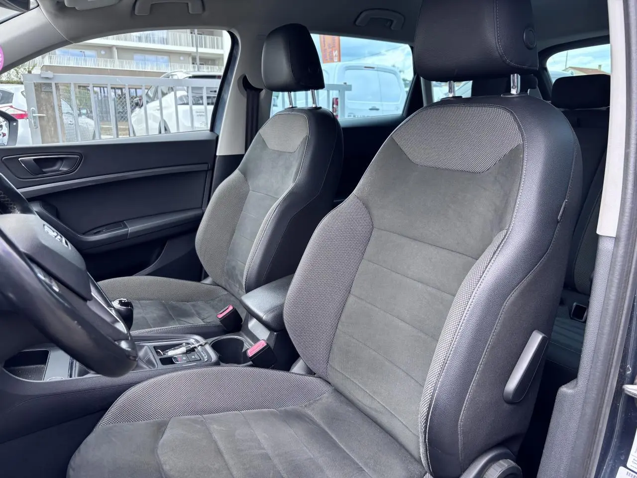 Vue intérieure côté gauche du SEAT Ateca 2019, sièges en textile gris foncé avec accoudoir central.