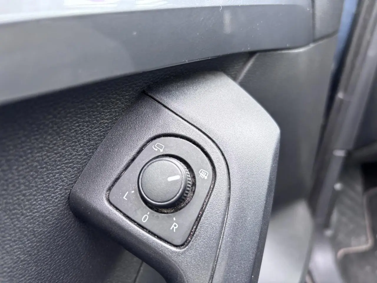 Gros plan sur le bouton de réglage des rétroviseurs côté conducteur du SEAT Ateca gris foncé, intérieur avant gauche.
