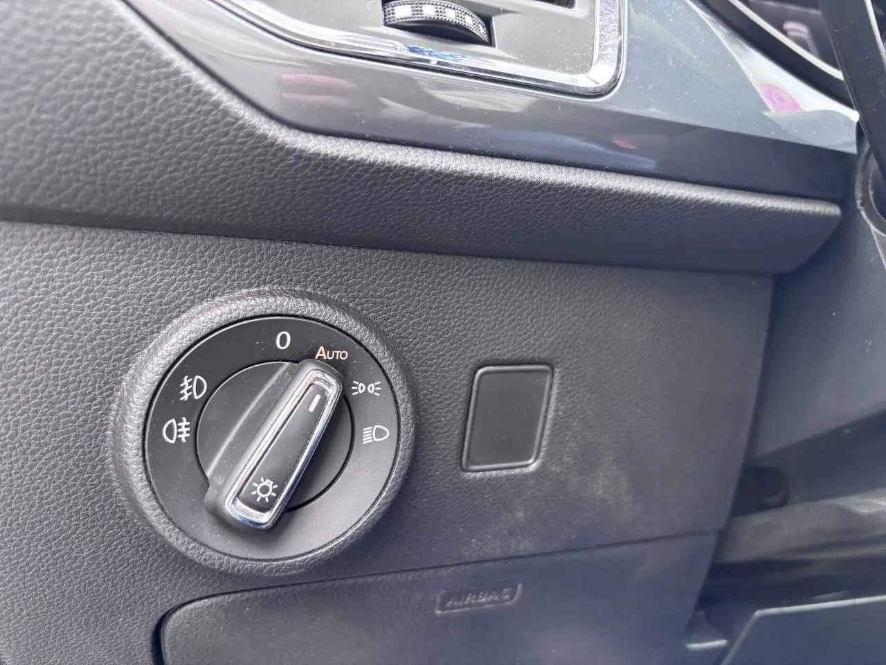 Gros plan sur le bouton de commande des phares à gauche du tableau de bord du SEAT Ateca gris foncé.