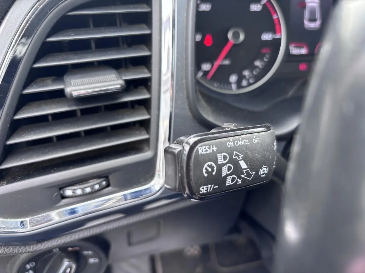 Gros plan sur la commande de régulateur de vitesse à gauche du volant dans l’habitacle gris foncé du SEAT Ateca 2019.