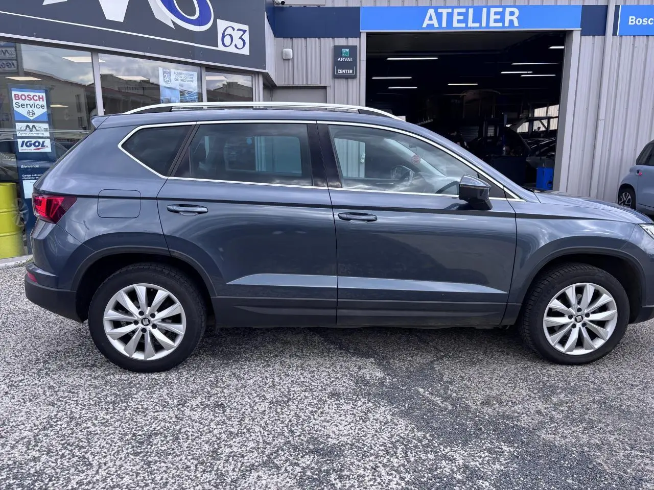 Vue de profil côté gauche d'un SEAT Ateca gris foncé garé devant un atelier Bosch Service.