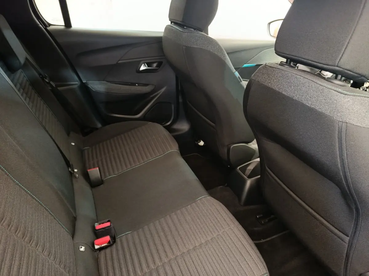 Vue intérieure arrière de la Peugeot 208 PureTech 100 noire, montrant la banquette et les dossiers des sièges avant.