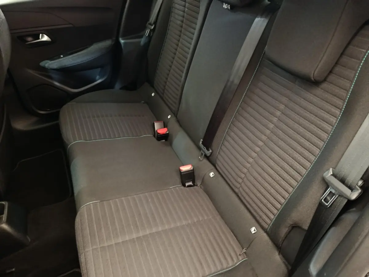 Vue intérieure sur la banquette arrière noire de la Peugeot 208 PureTech 100 S&S Style avec ceintures et appuie-têtes visibles.