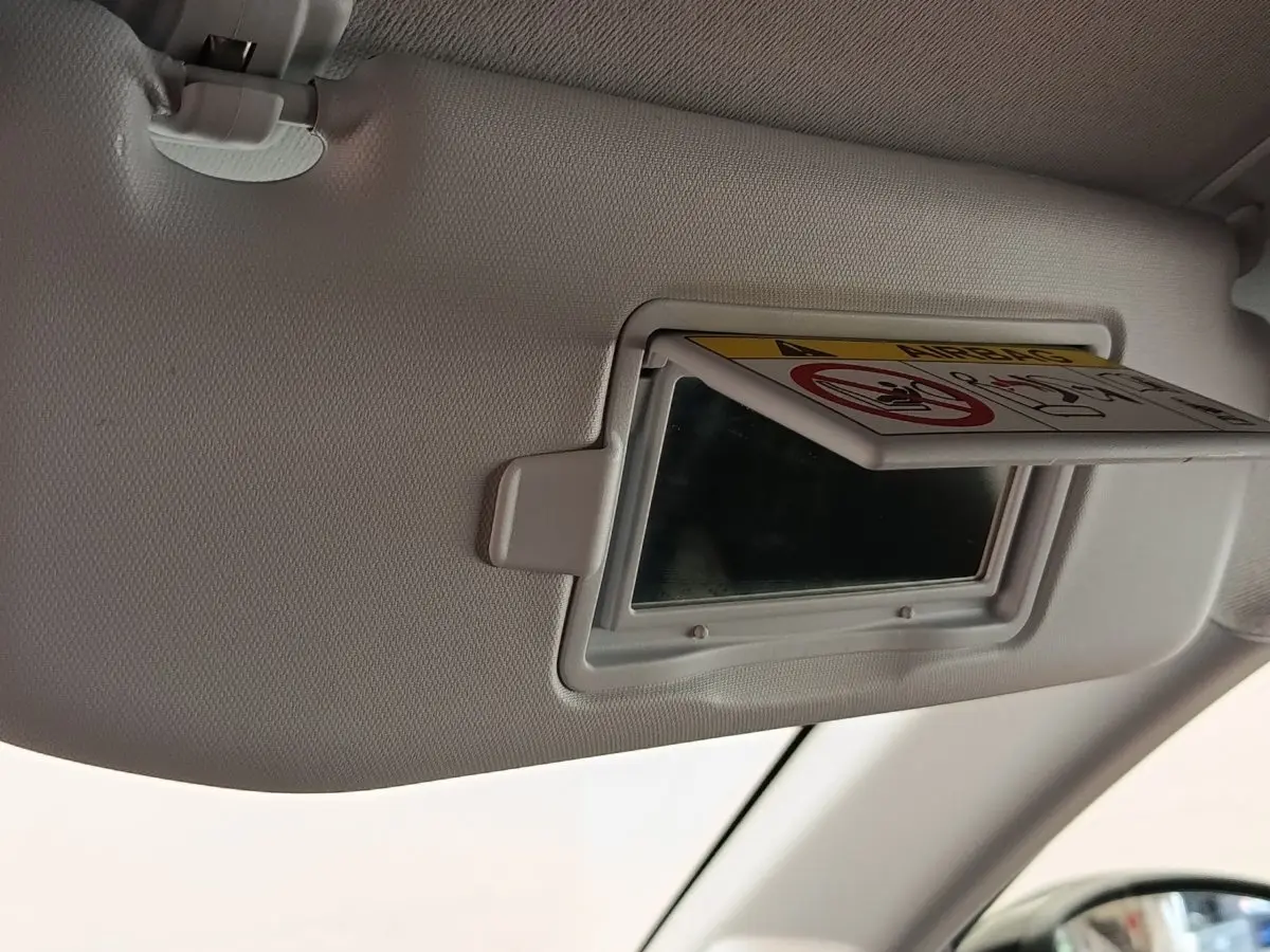 Détail du pare-soleil côté conducteur avec miroir de courtoisie et avertissement airbag dans une Peugeot 208 noire.