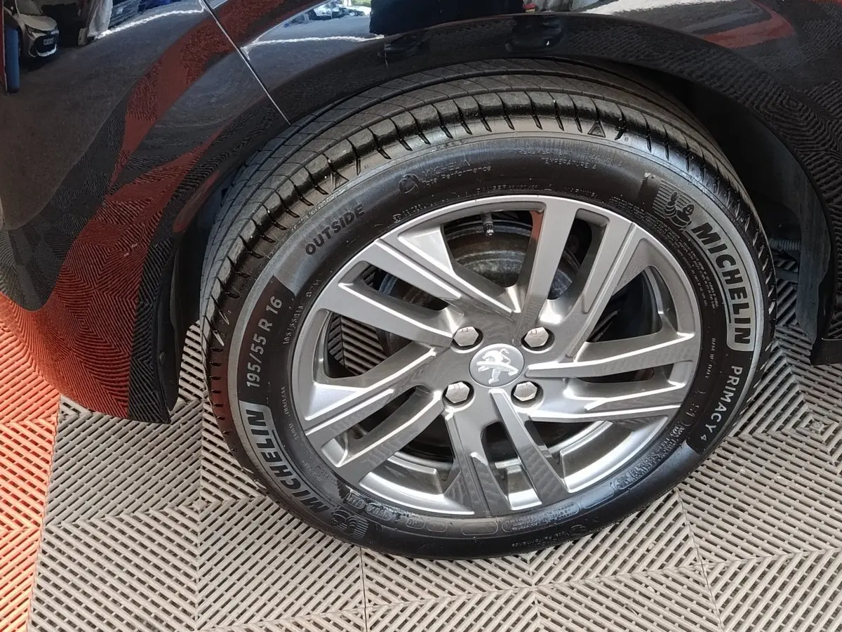 Gros plan sur la roue arrière gauche d'une Peugeot 208 noire, jante alliage argentée et pneu Michelin.
