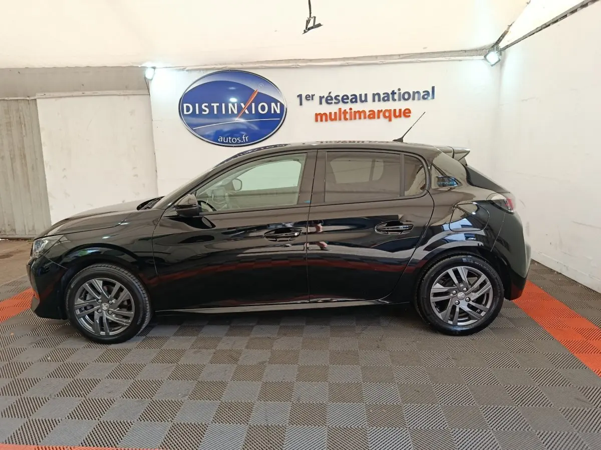 Profil côté gauche d'une Peugeot 208 PureTech 100 S&S Style noire, stationnée en intérieur sur sol damier.