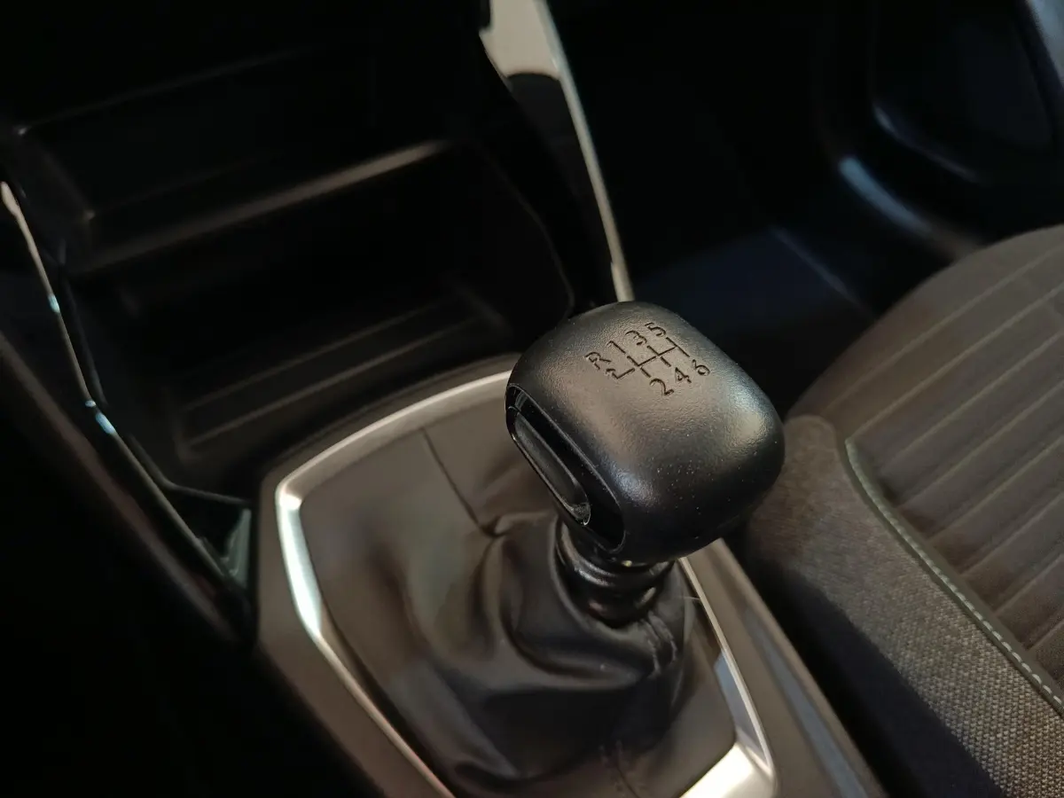 Gros plan sur levier de vitesses manuel noir dans Peugeot 208 PureTech 100 S&S Style 2022, intérieur sombre.