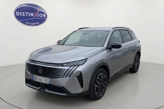 Vue 3/4 avant droite du Peugeot 5008 Hybrid gris 2025 avec calandre distinctive et jantes noires stylées.