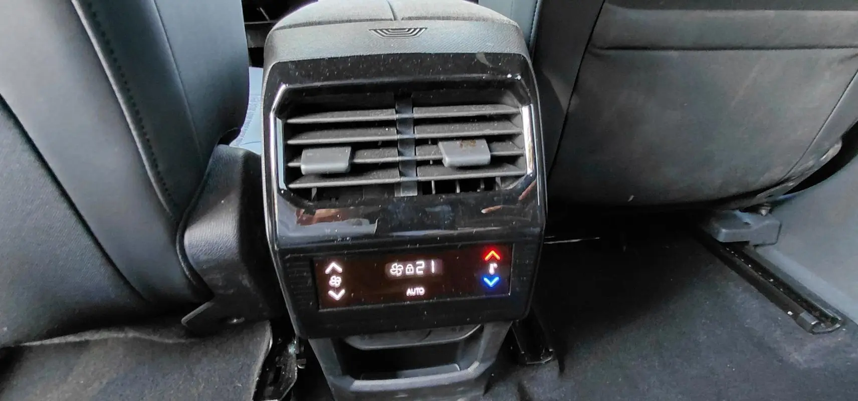 Vue rapprochée de la console arrière grise du Peugeot 5008 Hybrid 2025 avec commandes de climatisation digitale.