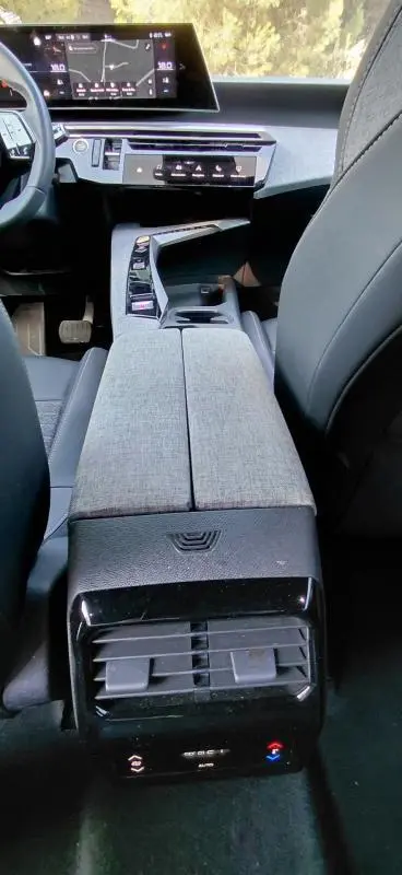 Vue intérieure arrière du Peugeot 5008 Hybrid gris 2025, mettant en valeur la console centrale et les commandes climatisation arrière.