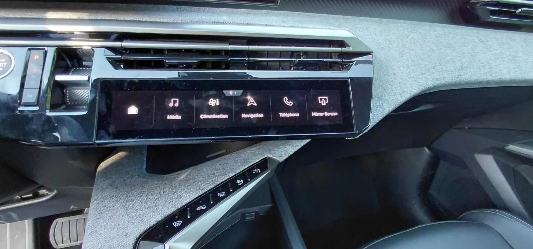 Vue rapprochée de la console centrale du Peugeot 5008 Hybrid 2025, écran tactile et finition tissu gris.