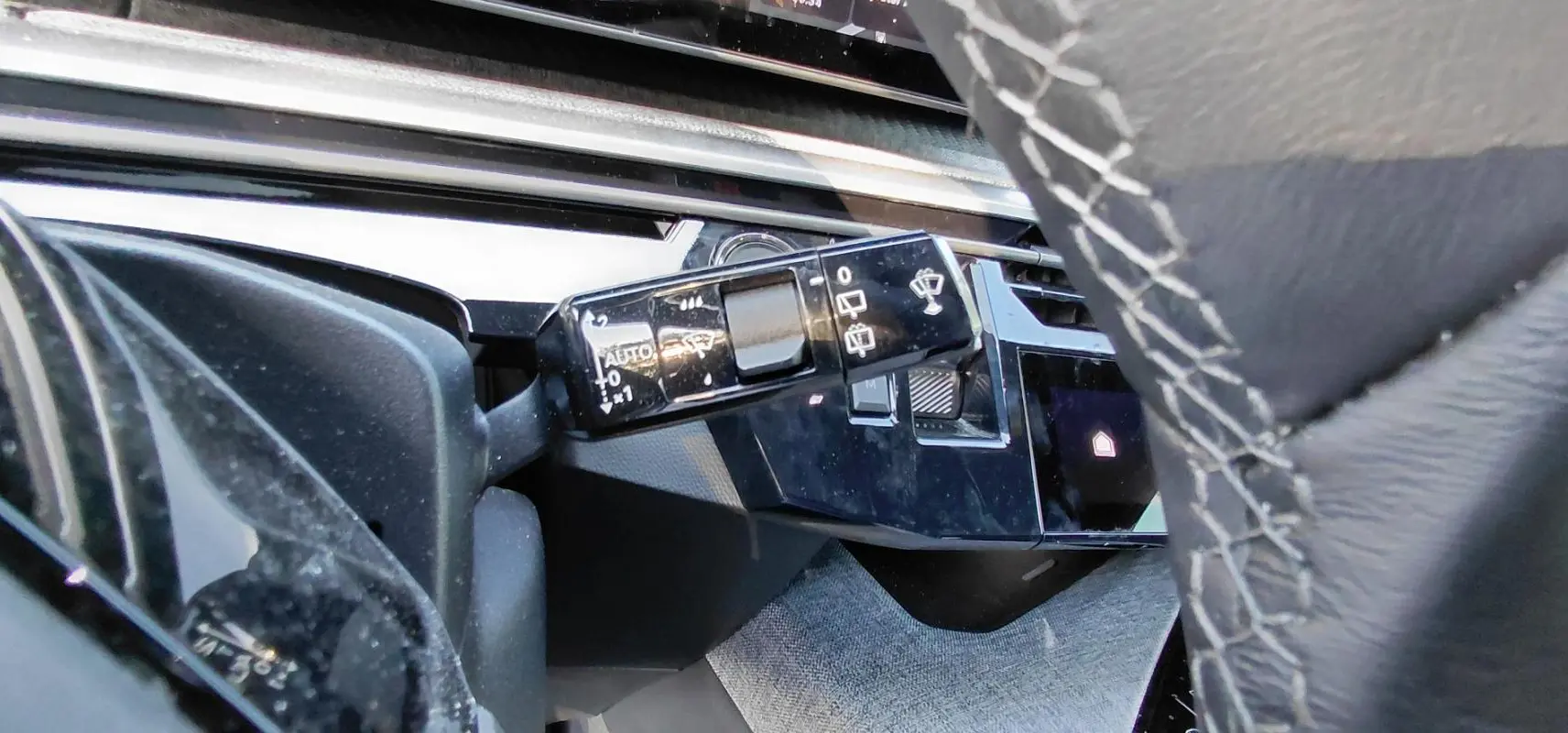 Gros plan sur la commande des essuie-glaces à gauche du volant en cuir gris du Peugeot 5008 Hybrid 2025.
