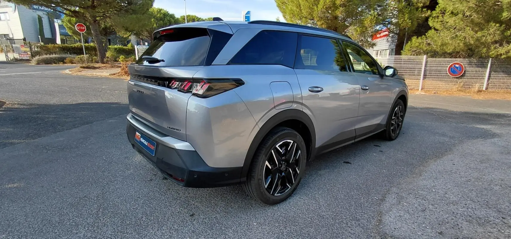 Peugeot 5008 Hybrid gris 3/4 arrière droit, mettant en valeur ses feux arrière distinctifs et ses jantes noires.