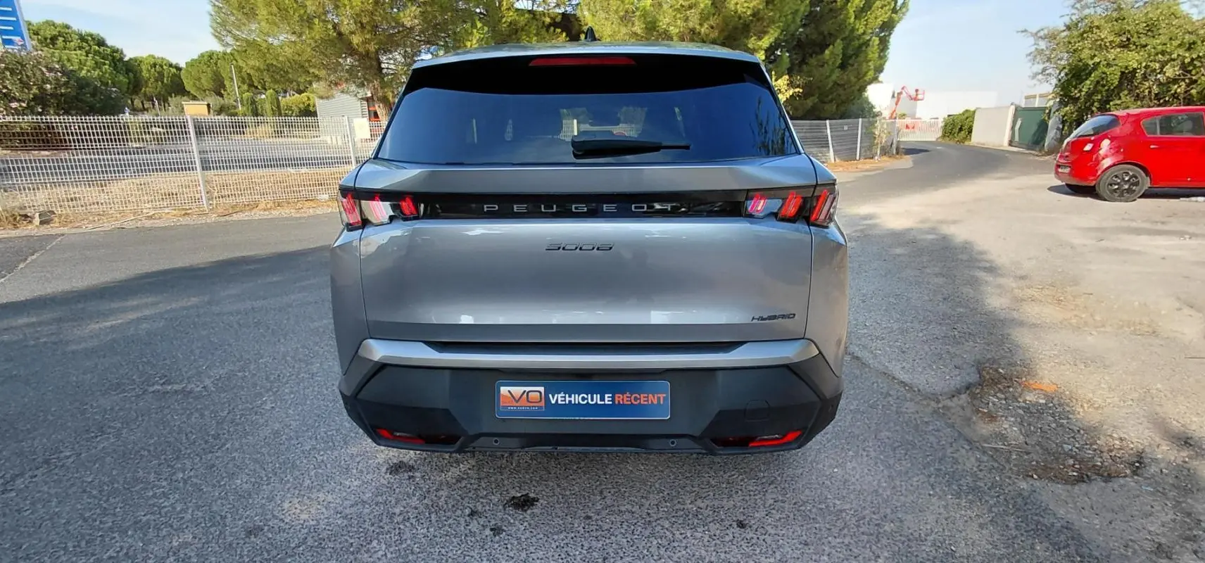 Vue arrière d'un Peugeot 5008 gris 2025 avec feux arrière à griffes et logo Peugeot lumineux.