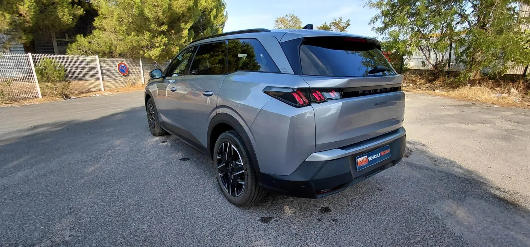 Peugeot 5008 gris en 3/4 arrière droit, mettant en valeur ses feux arrière à griffes et ses jantes noires.