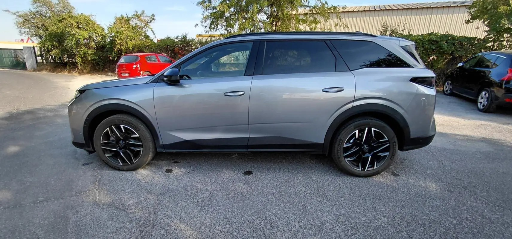 Peugeot 5008 Hybrid gris vue de profil côté gauche, soulignant ses jantes noires et lignes modernes.