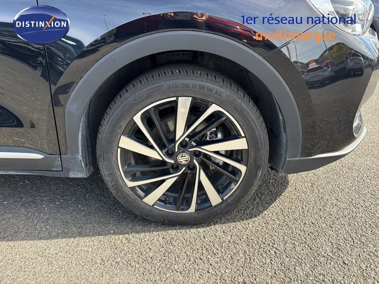 Gros plan sur la roue avant droite du MG ZS 1.5L HYBRID+ 197CH Luxury en Pebble Black Metal avec jante alliage bicolore.