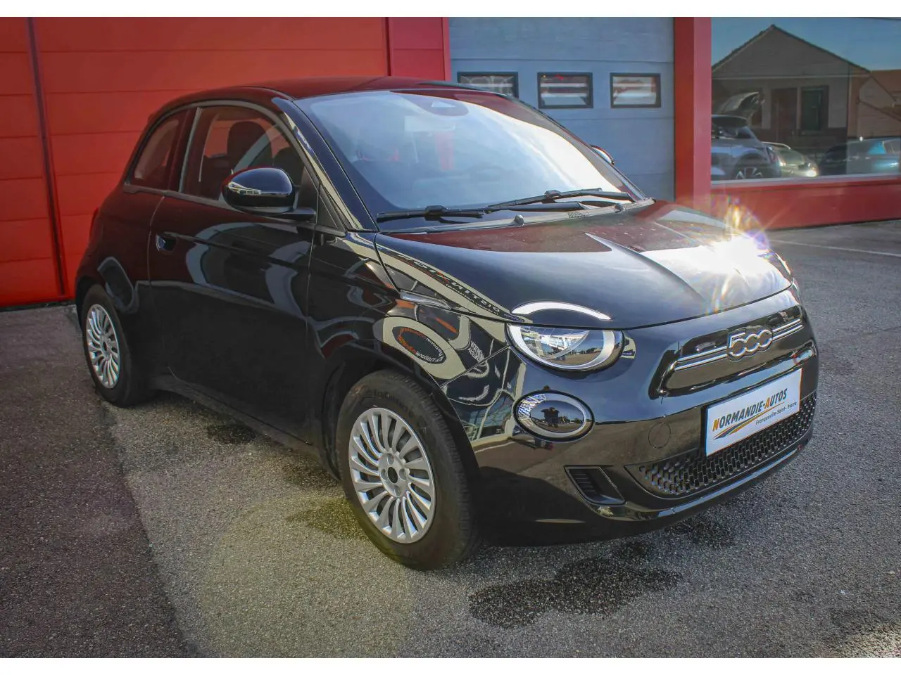 Fiat 500 électrique noire vue 3/4 avant droit, avec jantes alliage et logo 500 chromé sur calandre.