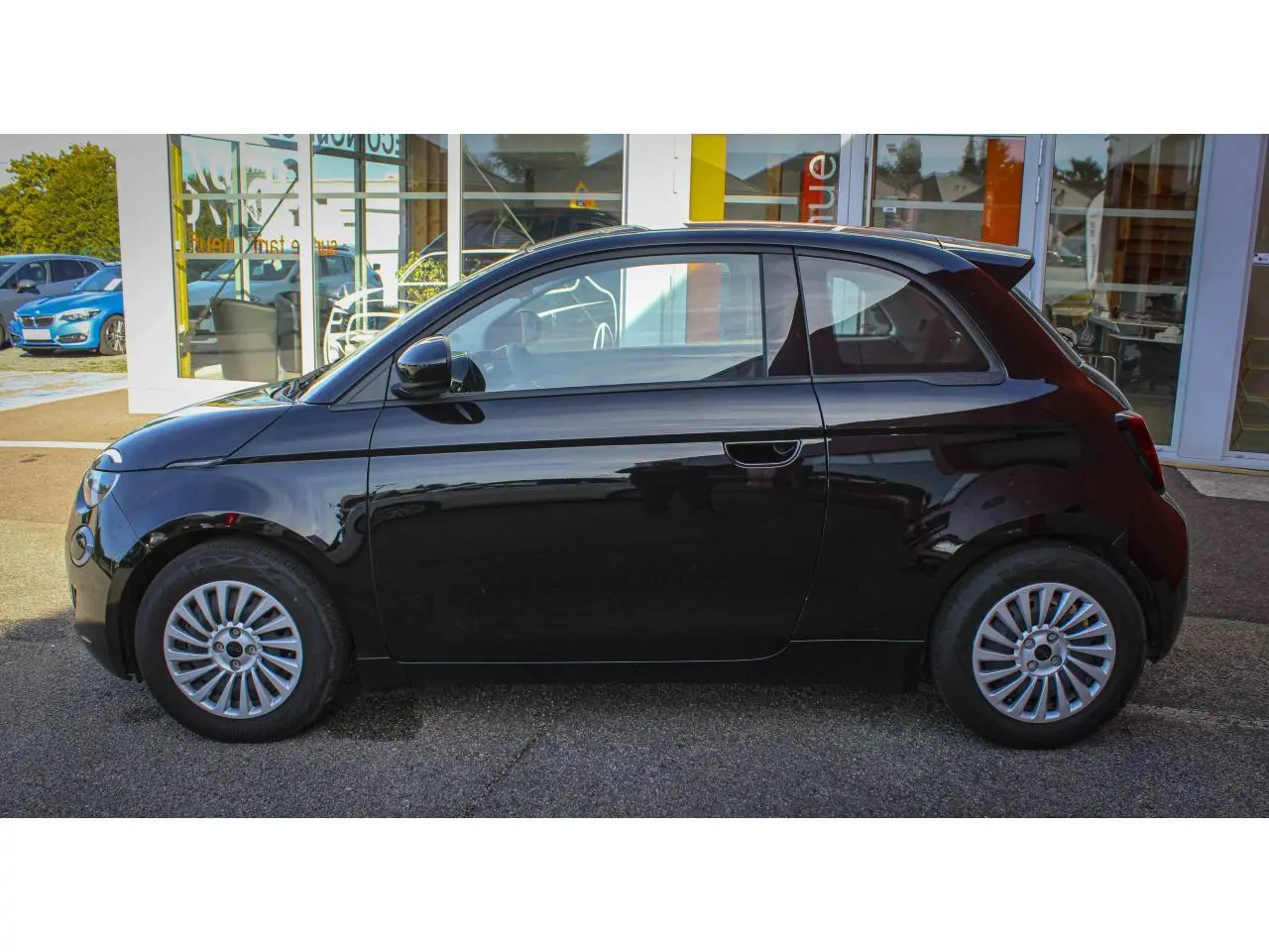 Profil côté gauche de la Fiat 500 électrique noire 2023 avec jantes alliage 16 pouces et poignées dissimulées.