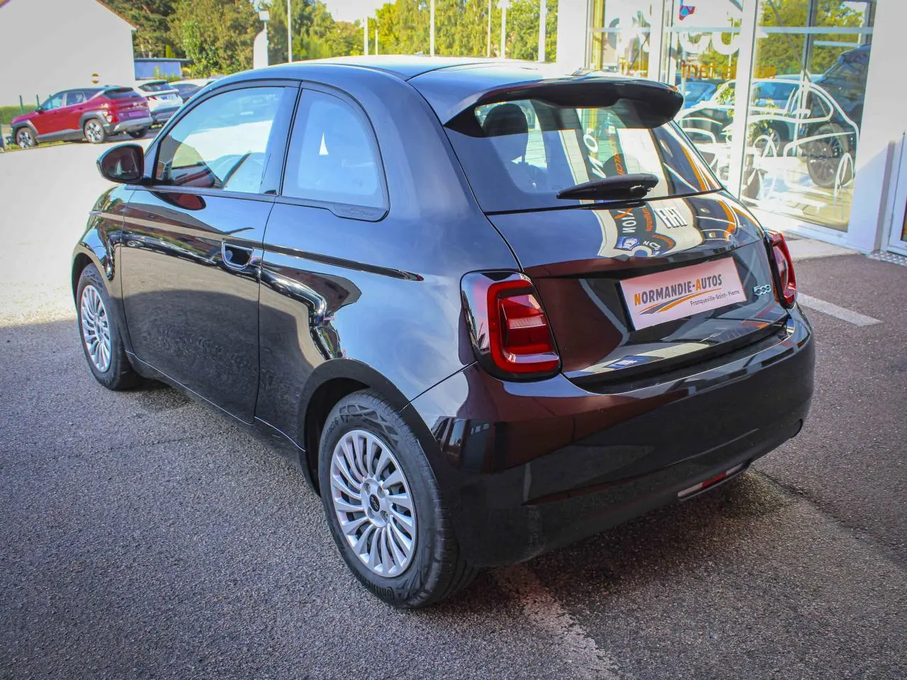 Vue 3/4 arrière droite de la Fiat 500 électrique noire 2023 avec jantes alliage et feux arrière LED distinctifs.