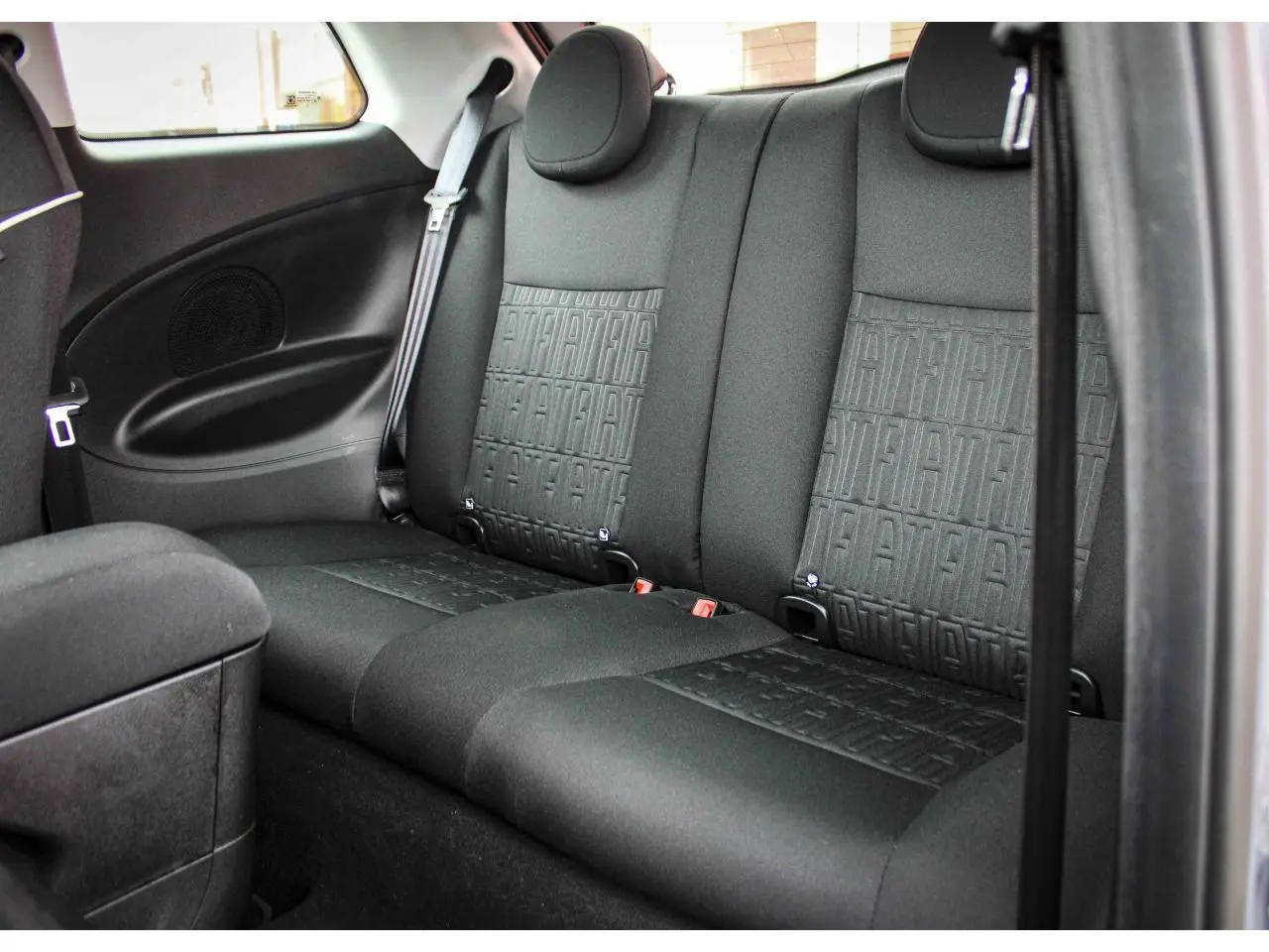 Vue intérieure arrière montrant les sièges arrière noirs avec motif FIAT en tissu dans une Fiat 500 électrique 2023.