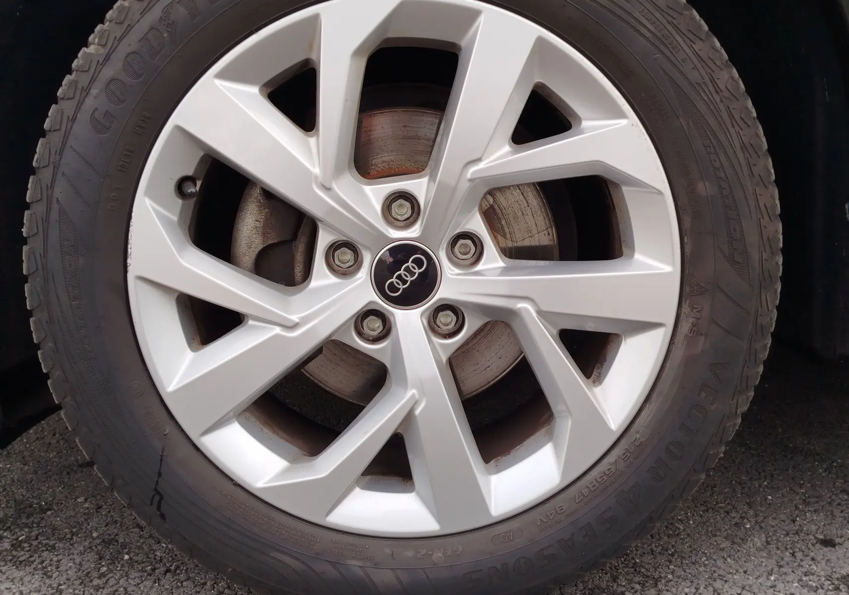 Gros plan sur la jante argentée de l'Audi Q2 noir mito metal, avec logo Audi au centre et pneu Goodyear visible.