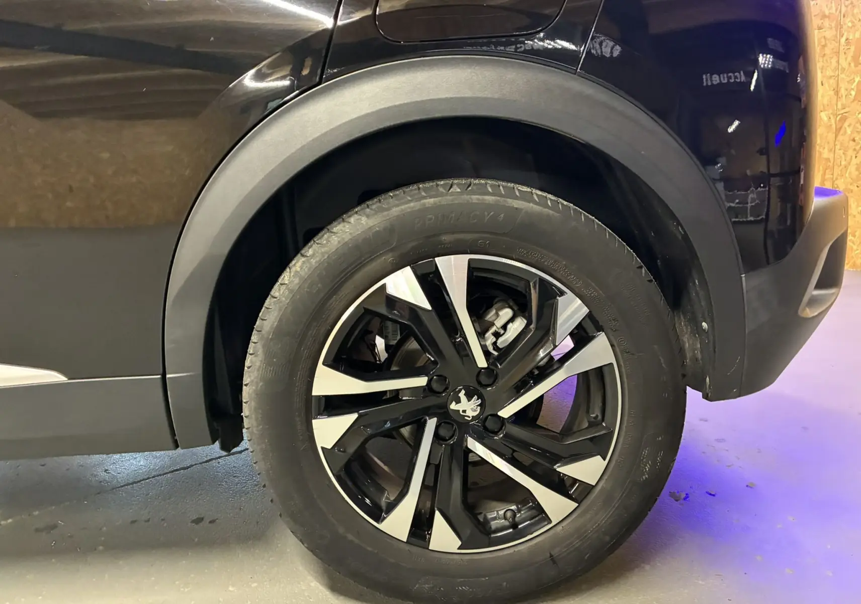 Gros plan sur la roue arrière droite noire du Peugeot 2008 1.5 BlueHDi 130 GT Line avec jante alliage bicolore.