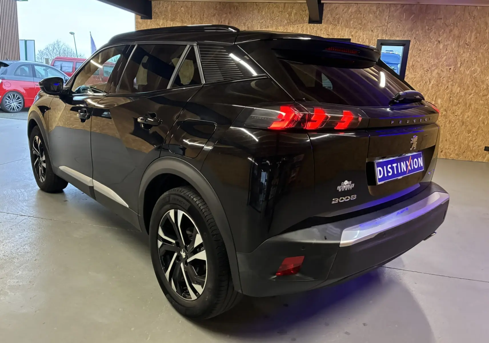 Vue 3/4 arrière droite d'un Peugeot 2008 noir avec feux arrière LED et jantes bi-ton en intérieur garage.