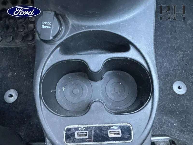 Gros plan sur la console centrale noire avec porte-gobelets et prises USB dans un Fiat 500 blanc.