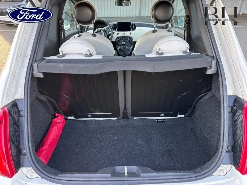 Vue arrière du coffre ouvert d'une Fiat 500 blanche Bossa Nova Pastel, montrant l'intérieur clair et les sièges avant.