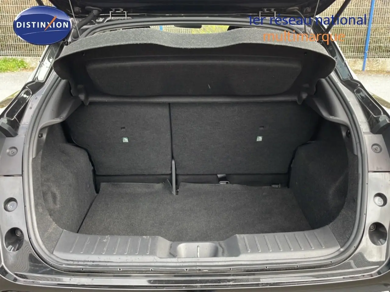 Coffre ouvert vu de l'arrière d'un Nissan Juke noir perle métal, montrant l'espace de chargement vide.