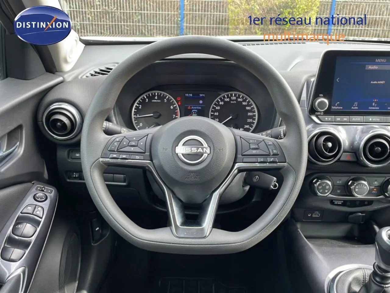 Vue intérieure centrée sur le volant Nissan Juke noir perle 2023, avec tableau de bord et écran tactile visible.