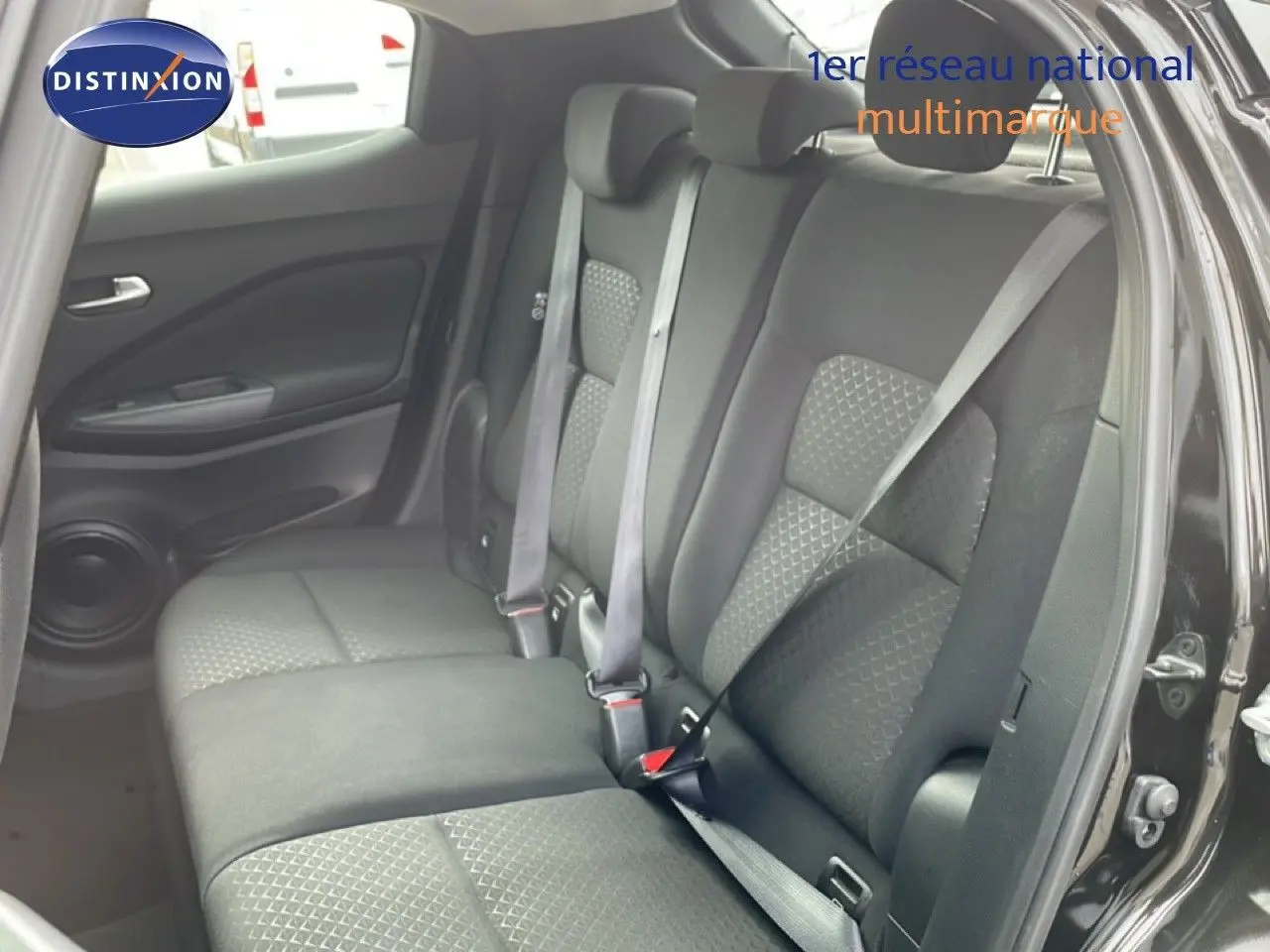 Vue intérieure montrant la banquette arrière en tissu gris noir du Nissan Juke 2023, porte arrière ouverte côté droit.