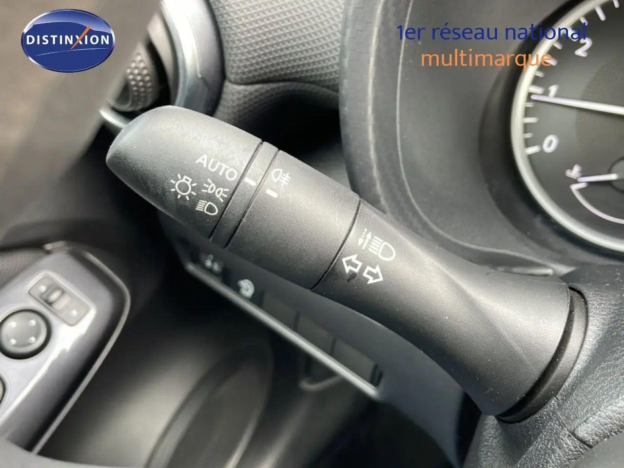 Gros plan sur la commande des feux et clignotants dans l’habitacle noir perle métal du Nissan Juke 2023.