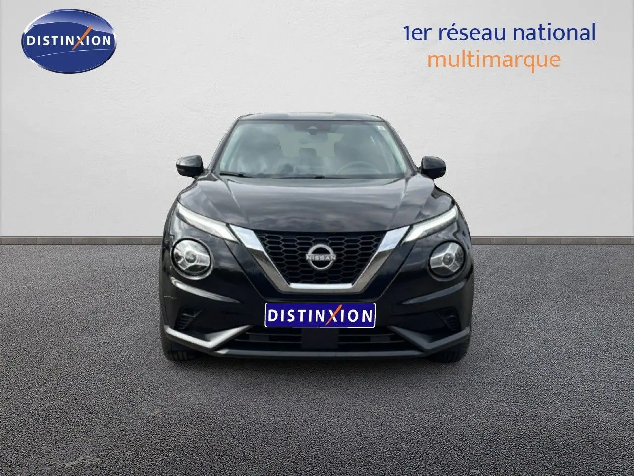 Vue frontale d'un Nissan Juke noir perle métal 2023 avec calandre en V chromée et phares ronds distinctifs.