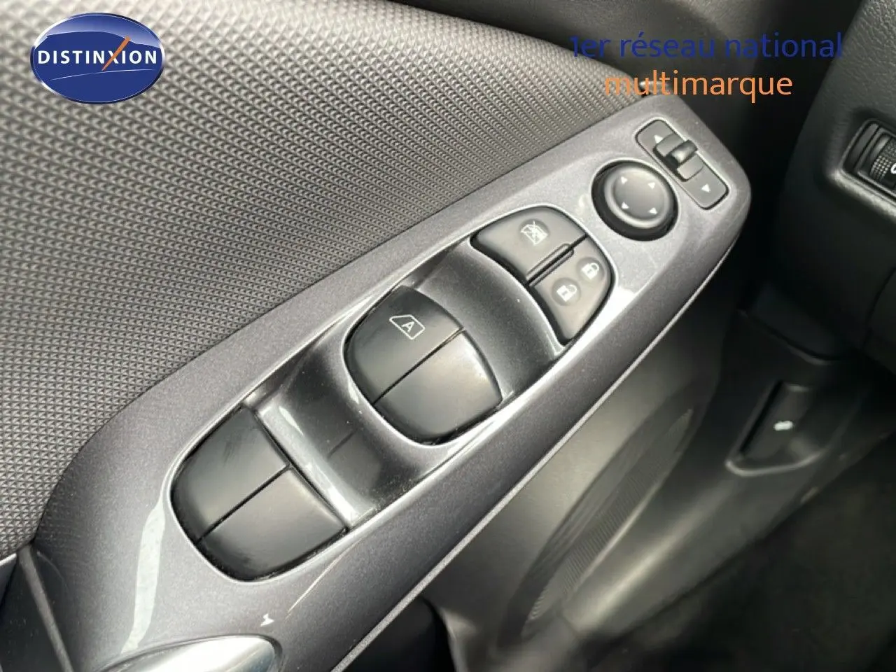 Vue rapprochée des commandes de lève-vitres et rétroviseurs sur la porte intérieure d'une Nissan Juke noire perle métal.