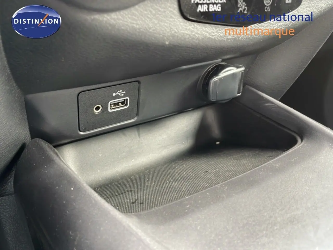 Gros plan sur la prise USB et l’allume-cigare dans l’espace de rangement intérieur noir du Nissan Juke 2023.