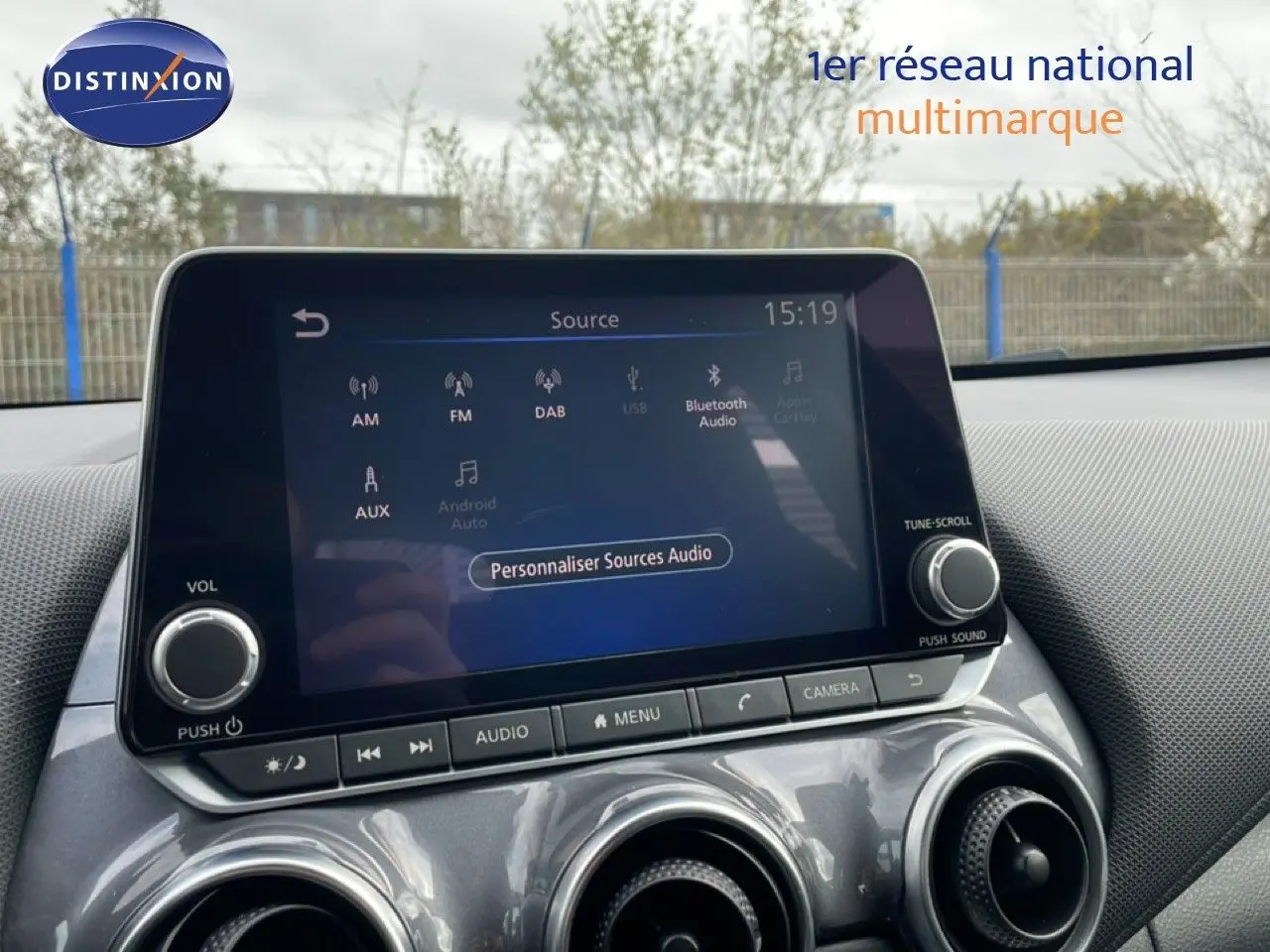 Écran tactile central du Nissan Juke 2023 en noir perle métal, avec commandes audio et ventilation visibles.