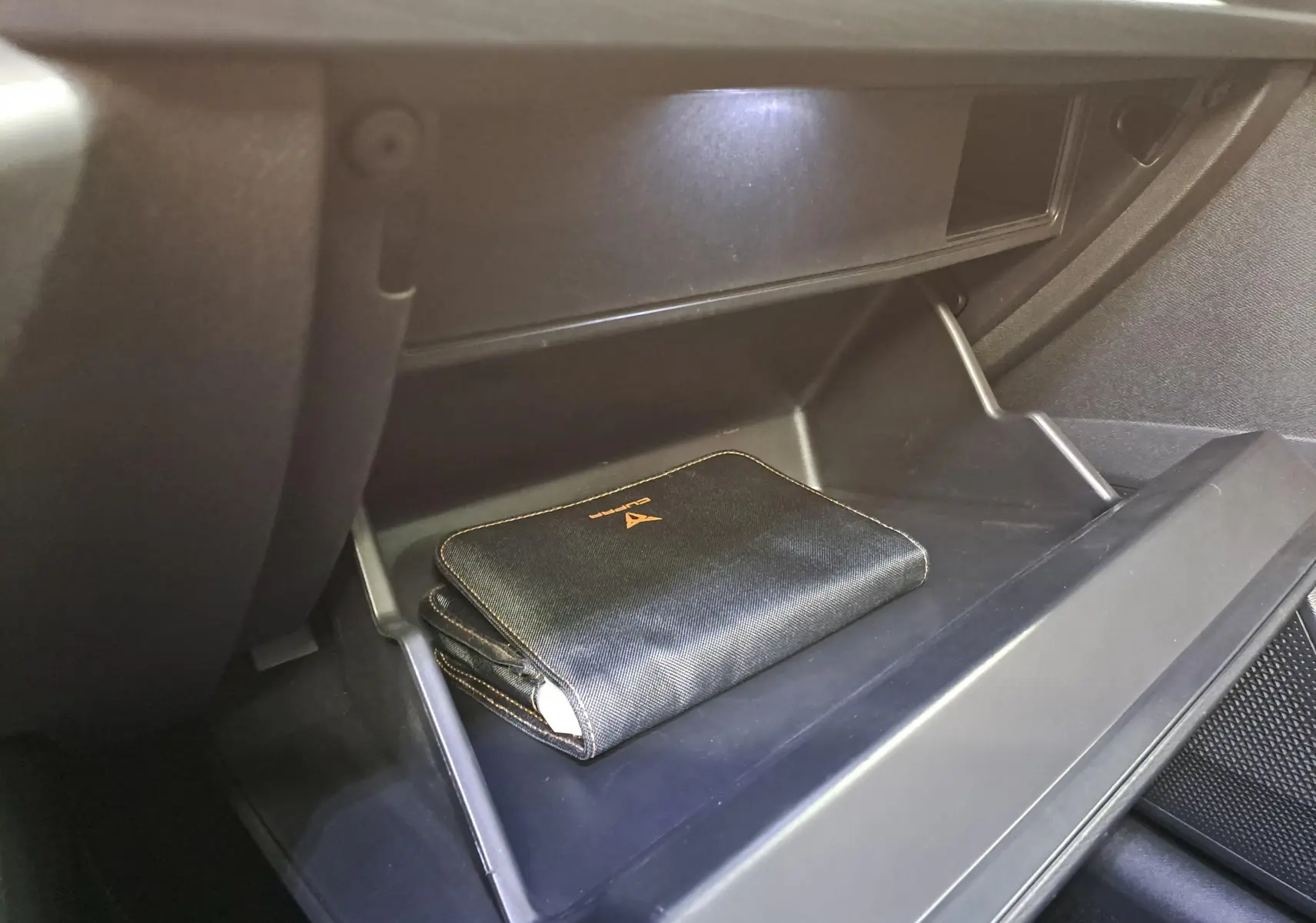 Gros plan sur la boîte à gants ouverte du CUPRA Formentor 2023 avec pochette noire et surpiqûres copper visible.