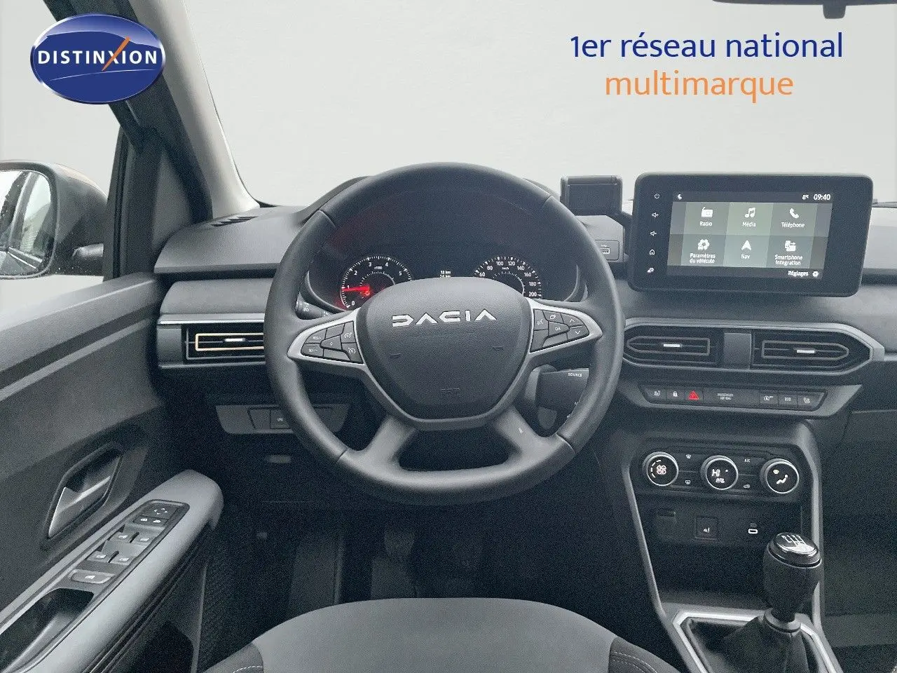 Vue intérieure centrée sur le volant DACIA et la console centrale avec écran tactile, ambiance noire moderne.