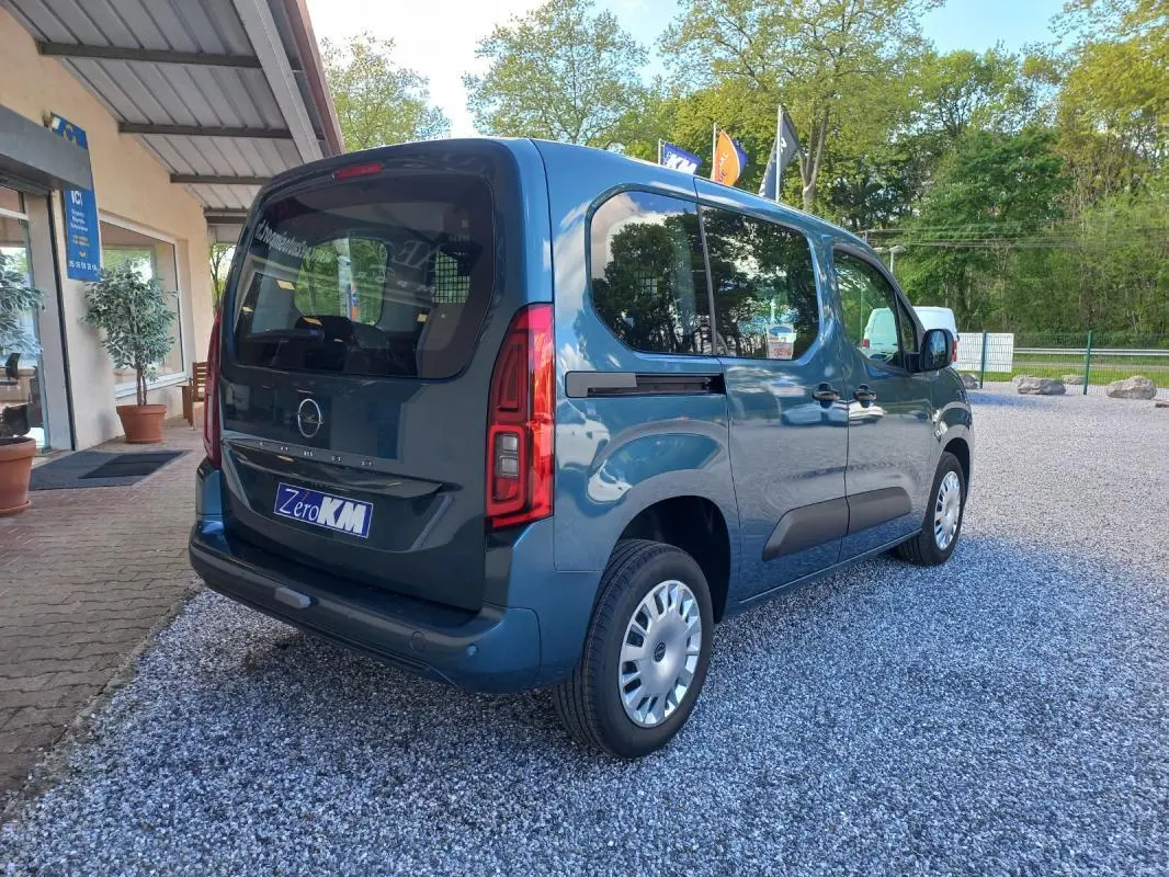 Vue 3/4 arrière droite d’un Opel Combo Life Elegance M bleu 2025, avec vitres teintées et logo Opel visible.