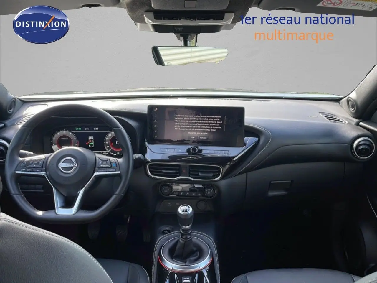 Vue intérieure avant du Nissan Juke 2025 noir Kuro Metal, mettant en valeur le volant, l'écran tactile et la boîte manuelle.