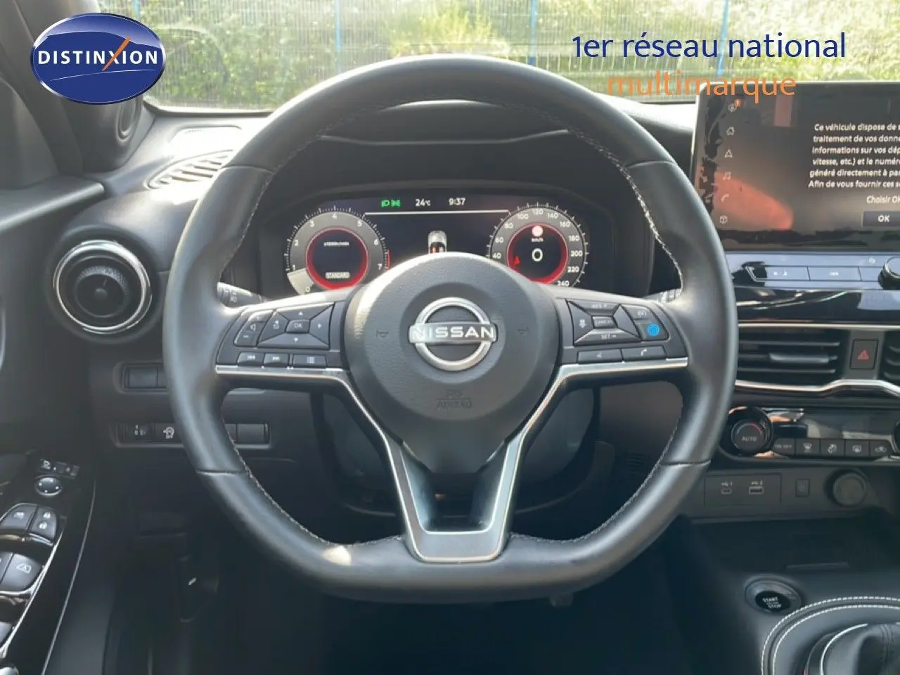 Vue intérieure centrée sur le volant cuir du Nissan Juke 2025 noir Kuro Metal avec tableau de bord digital et écran tactile.