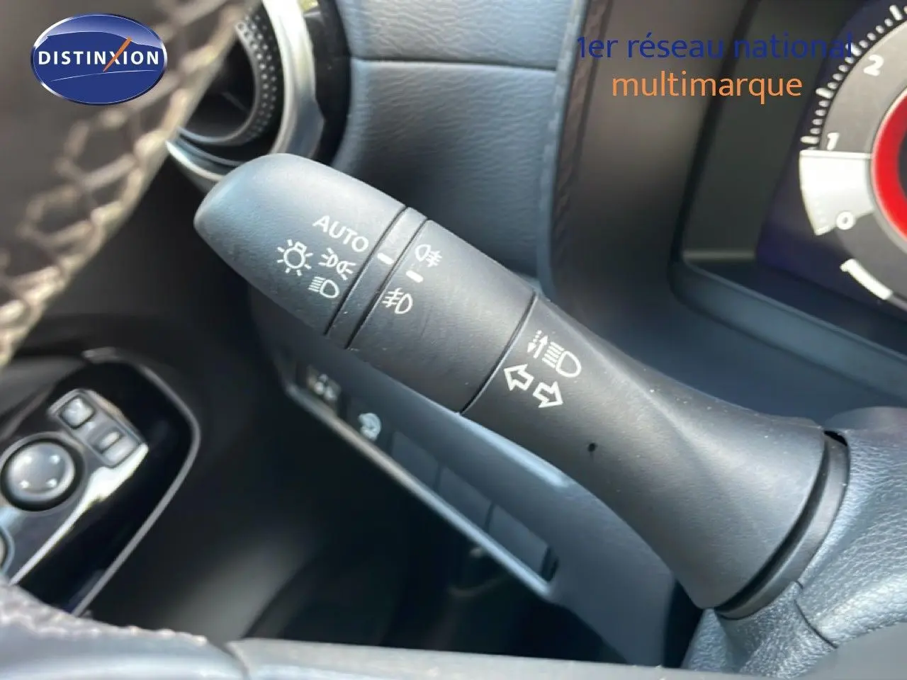 Gros plan sur la commande des feux et clignotants du Nissan Juke noir, intérieur avec volant et tableau de bord partiel.