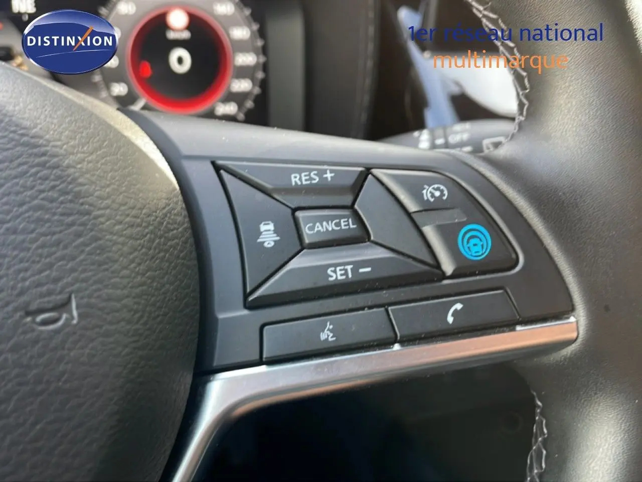Gros plan sur les commandes au volant du Nissan Juke 2025 noir Kuro Metal, avec régulateur de vitesse et commandes vocales.