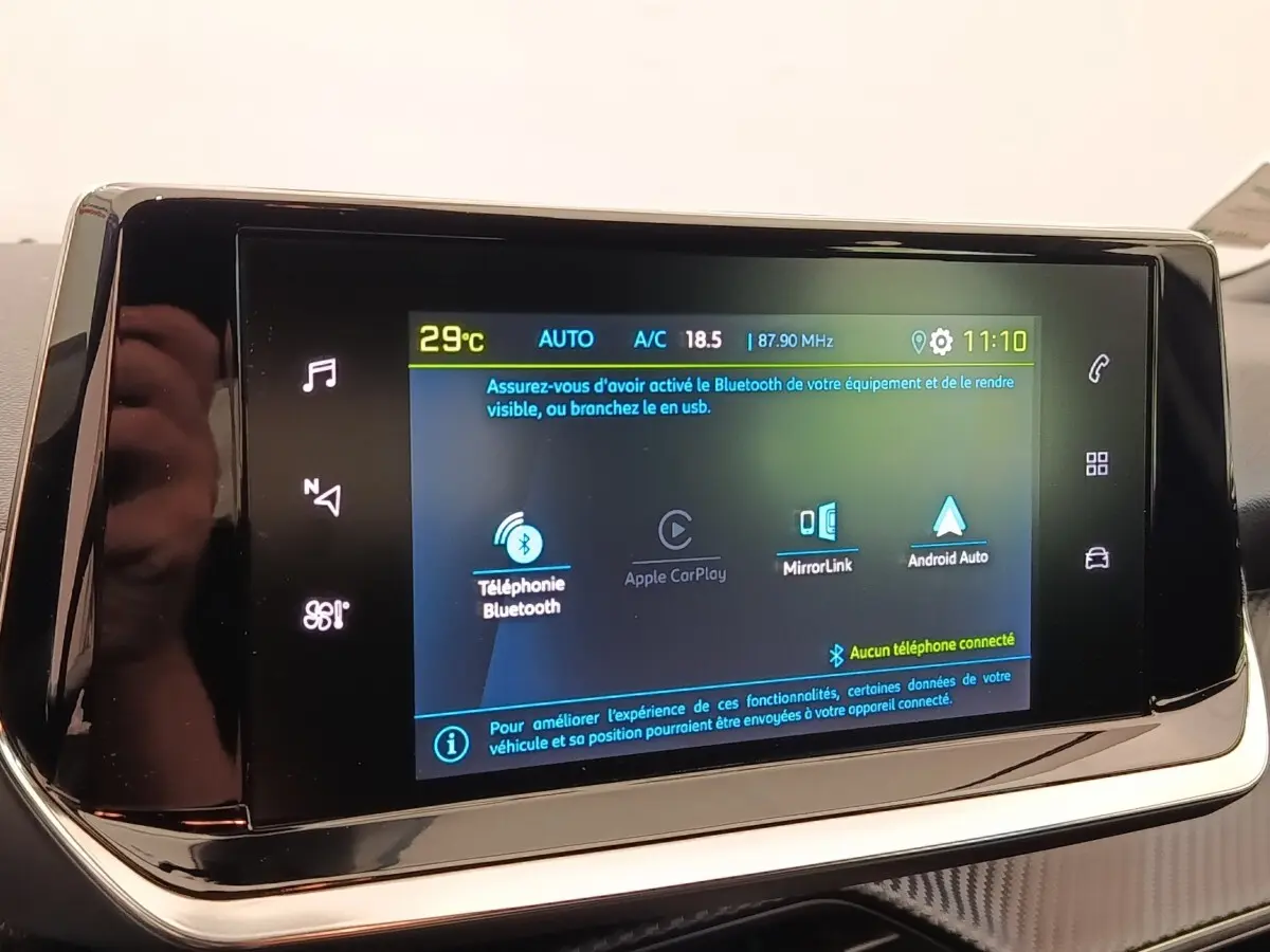 Écran tactile central du tableau de bord du Peugeot E-2008 gris clair, affichant les options Bluetooth et Apple CarPlay.