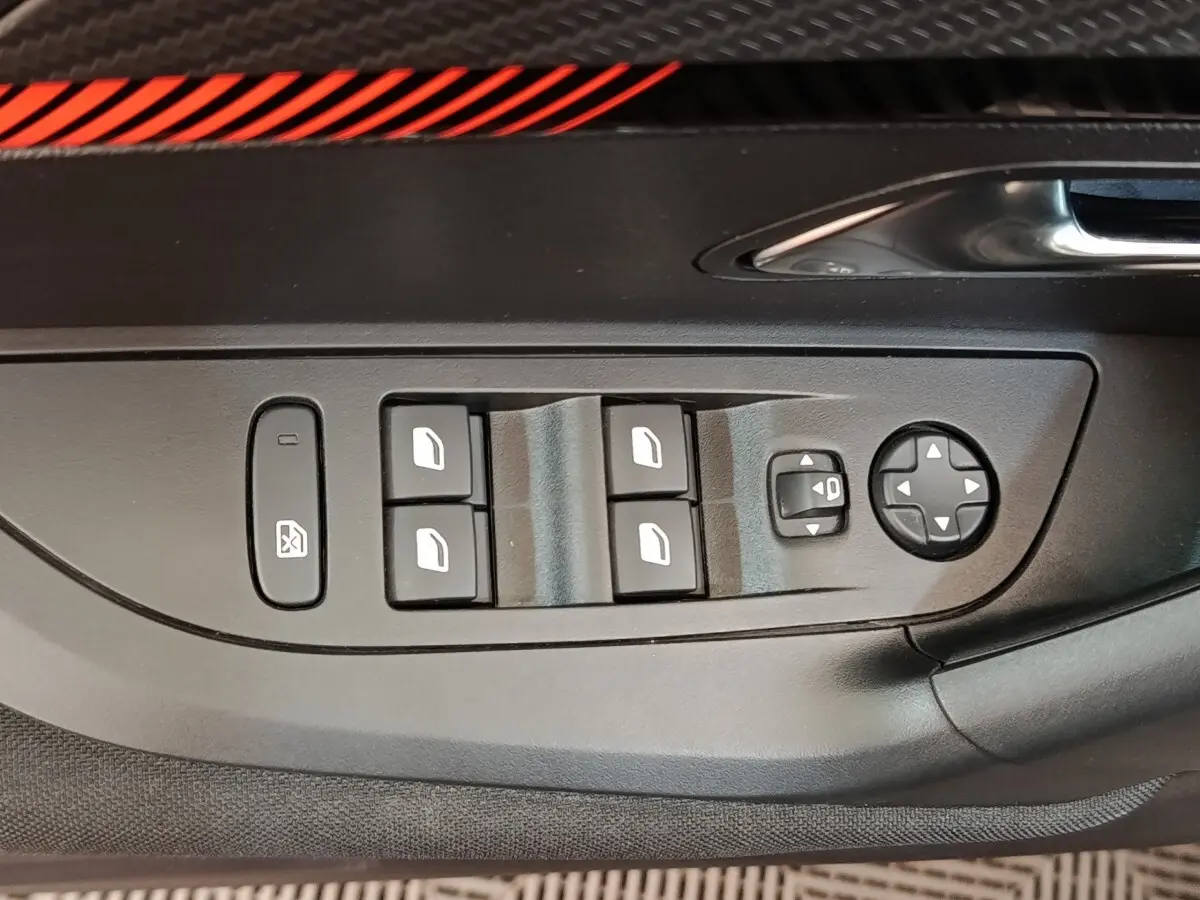 Gros plan sur les commandes de lève-vitres et rétroviseurs électriques côté conducteur du Peugeot E-2008 gris clair.